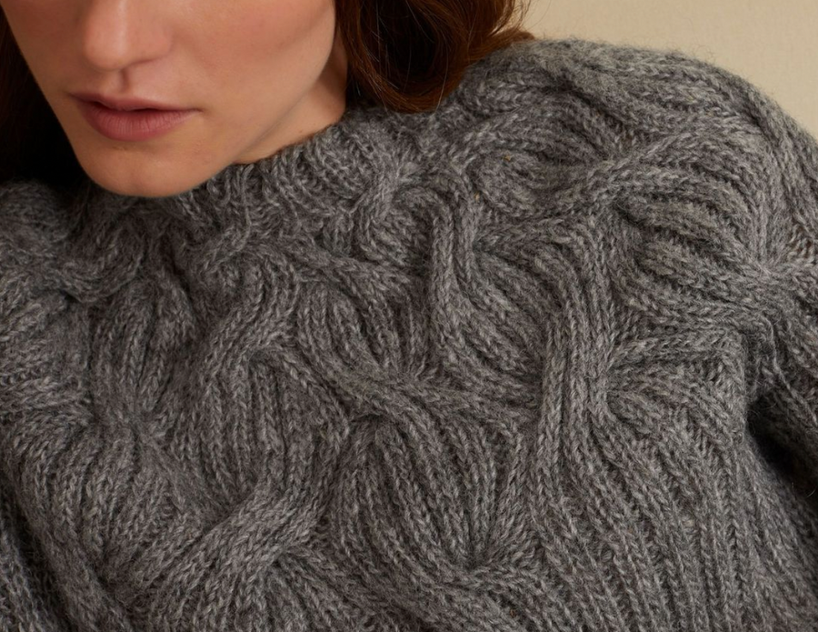 Woman wearing sustainably and ethically made wool cable knit sweater from wearwell personal stylist subscription membership and made in fair trade facility.