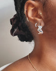 The model is wearing three pairs of smooth Ear Huggers in Silver. She is also wearing the Wave Hoops in silver. 