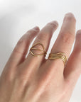 The model is wearing two Curve Rings and a Simple Stacking Ring on her ring finger. She's also wearing three curve rings sitting in the same way on her middle finger. All of the rings are gold.